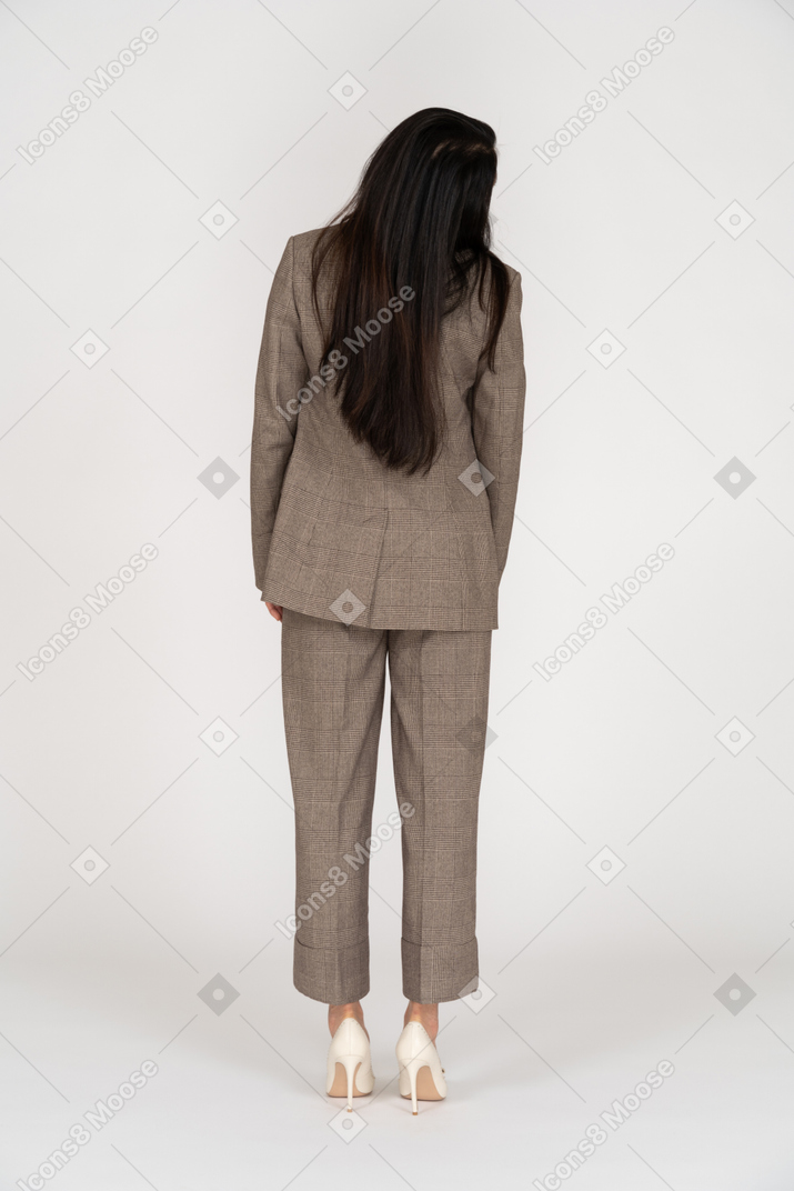Back view of a young lady in brown business suit turning head