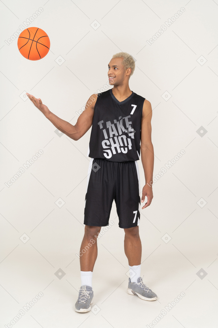 Three-quarter view of a young male basketball player throwing a ball