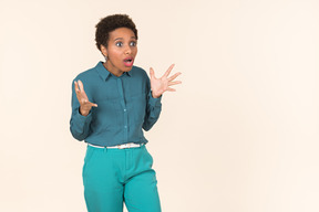 Black woman with a short haircut, wearing all blue, standing against a plain pastel background, looking emotional