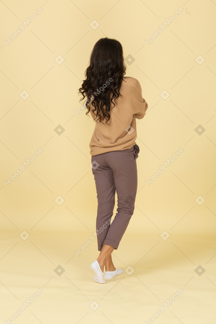 Back view of a dark-skinned  young female touching her face