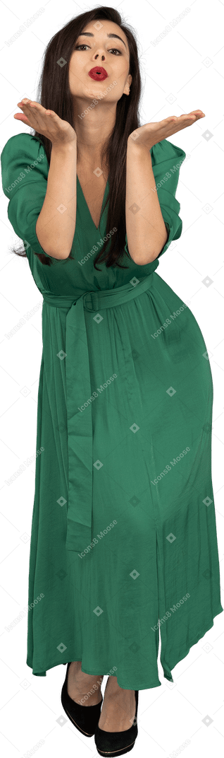 Vista frontal de una joven en vestido verde enviando un beso al aire