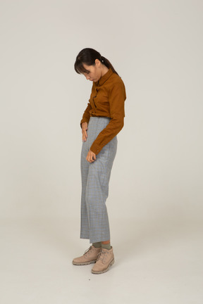 Side view of a young asian female in breeches and blouse putting hands in pockets