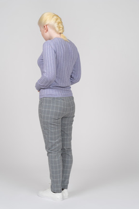 Three-quarter back view of a blonde woman looking down