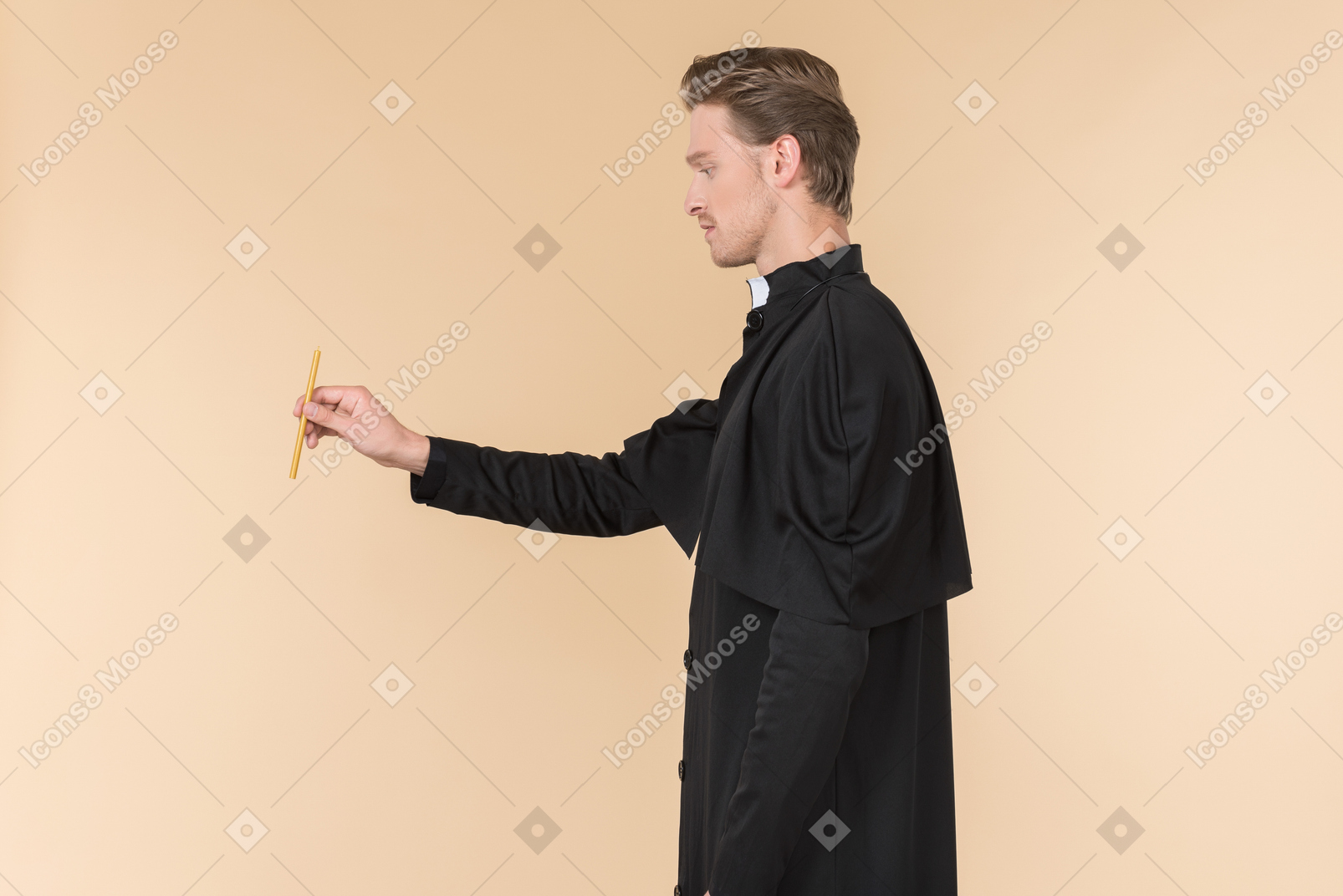 Catholic priest standing in profile and holding a candle