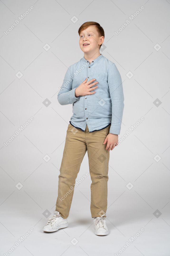 Вид сверху на симпатичного мальчика, позирующего с рукой на груди