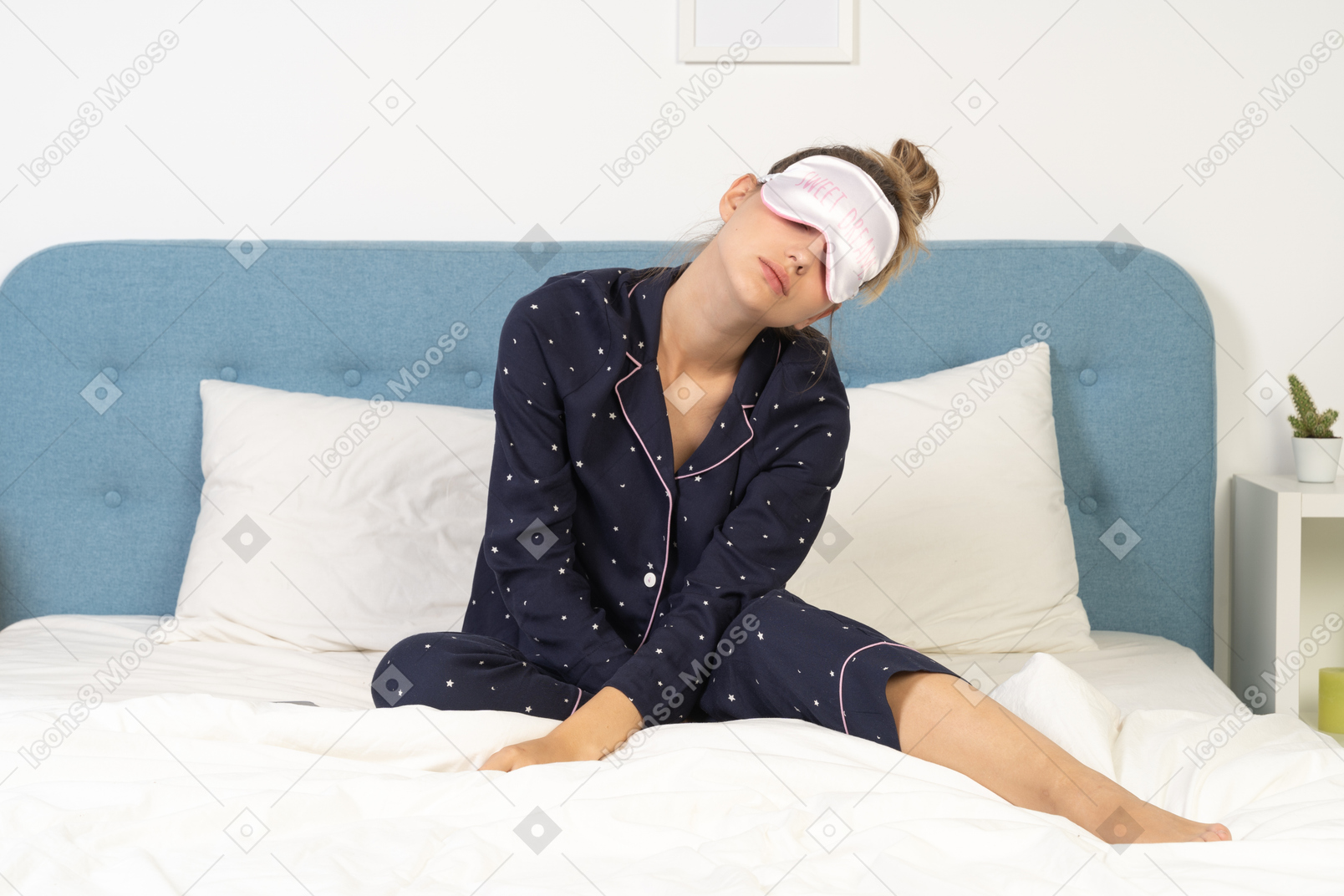 Front view of a young lady in pajamas putting on a sleeping mask
