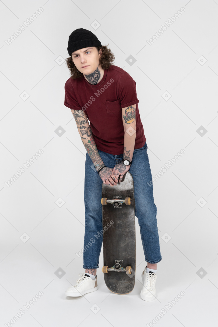 彼のスケートボードを持って立っているティーンエイジャー