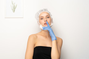 Young woman in scrub cap holding finger to lips