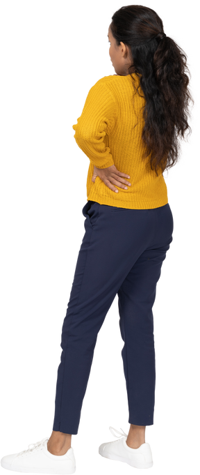 Back view of a thoughtful girl in casual clothes posing with hand on hip