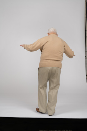 Rückansicht eines alten mannes in freizeitkleidung, der auf einem bein balanciert