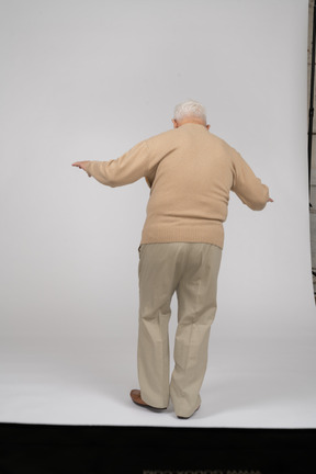 Vista posteriore di un uomo anziano in abiti casual in equilibrio su una gamba