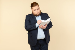 Übergewichtiger männlicher büroangestellter, der dokumente überarbeitet
