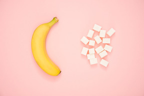 Banane et sucre en cubes sur fond contrasté