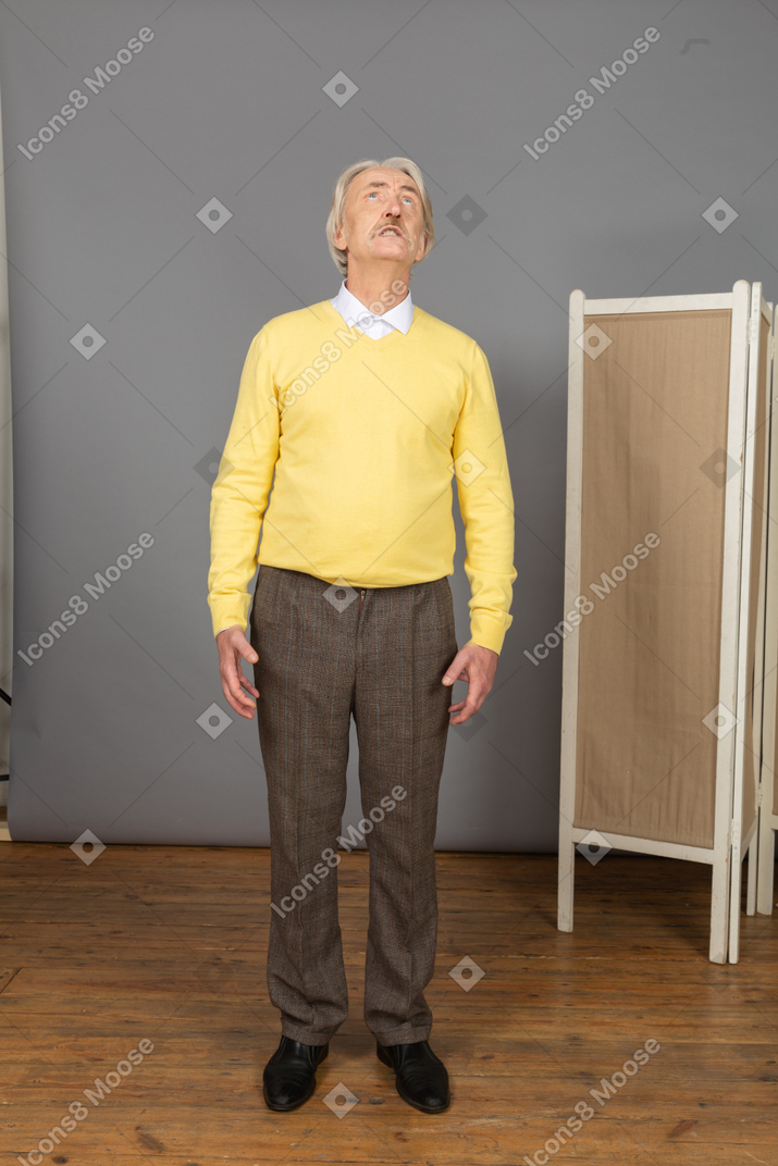 Front view of an impatient old man clenching teeth while raising head