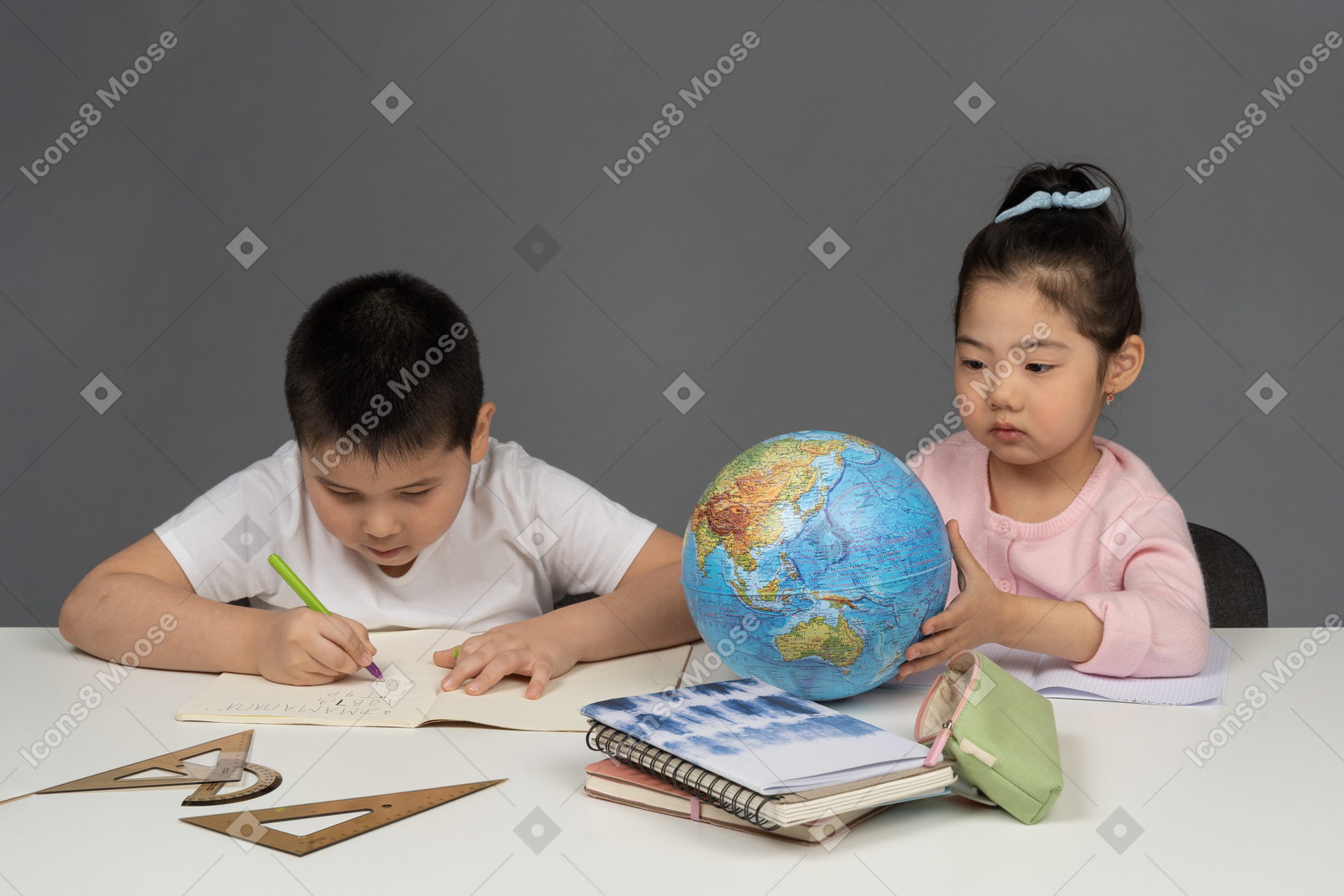 Menino fazendo sua lição de casa e menina olhando para um globo