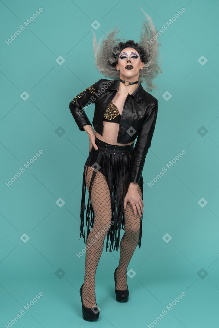 Drag queen in leather jacket shaking hair with hand on waist
