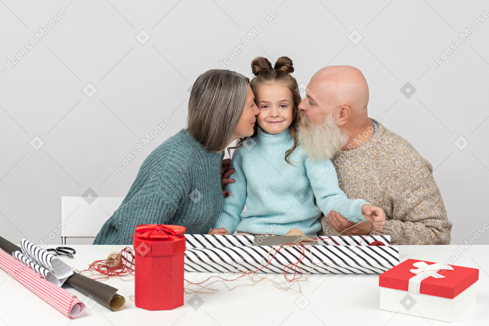 Бабушка и дедушка упаковывают подарки и целуют внучку