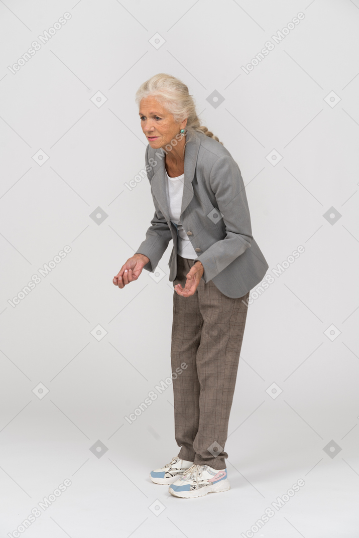 腰をかがめて何かを説明するスーツを着たおばあさんの側面図