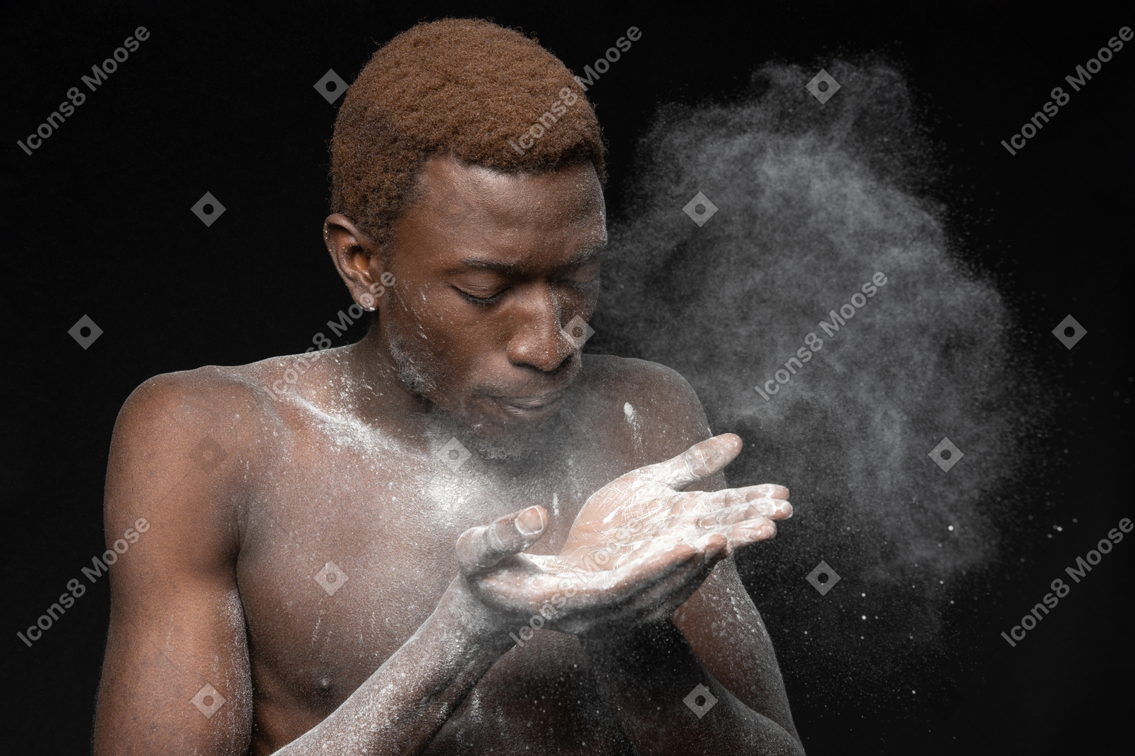 彼の手のひらから小麦粉を吹くアフリカの若い男性のクローズアップ