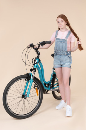 Teenage girl standing near blue bicycle