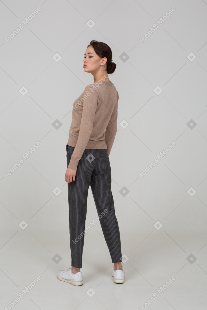Vista posteriore di una giovane donna in pullover e pantaloni che voltano le spalle