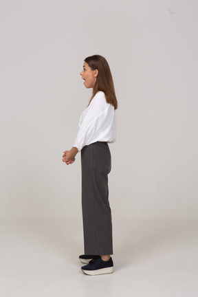 Vista lateral de uma jovem chocada com roupas de escritório, de mãos dadas