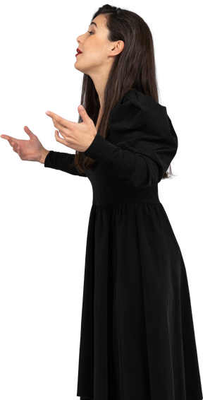 黒いドレスを着た身振りで示す若い女性の側面図