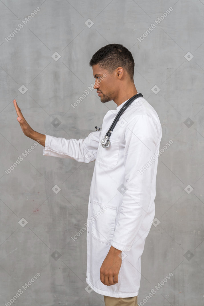 Side view of a male doctor showing stop hand