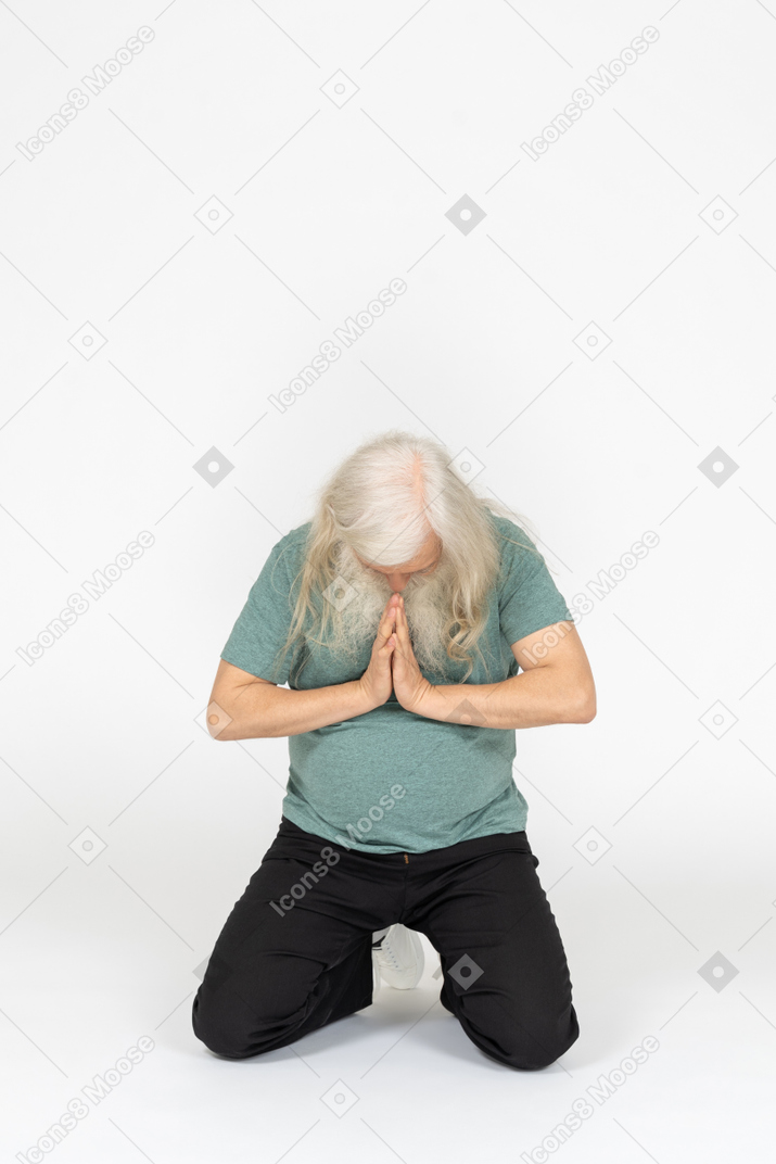 Front view of old man sitting and praying