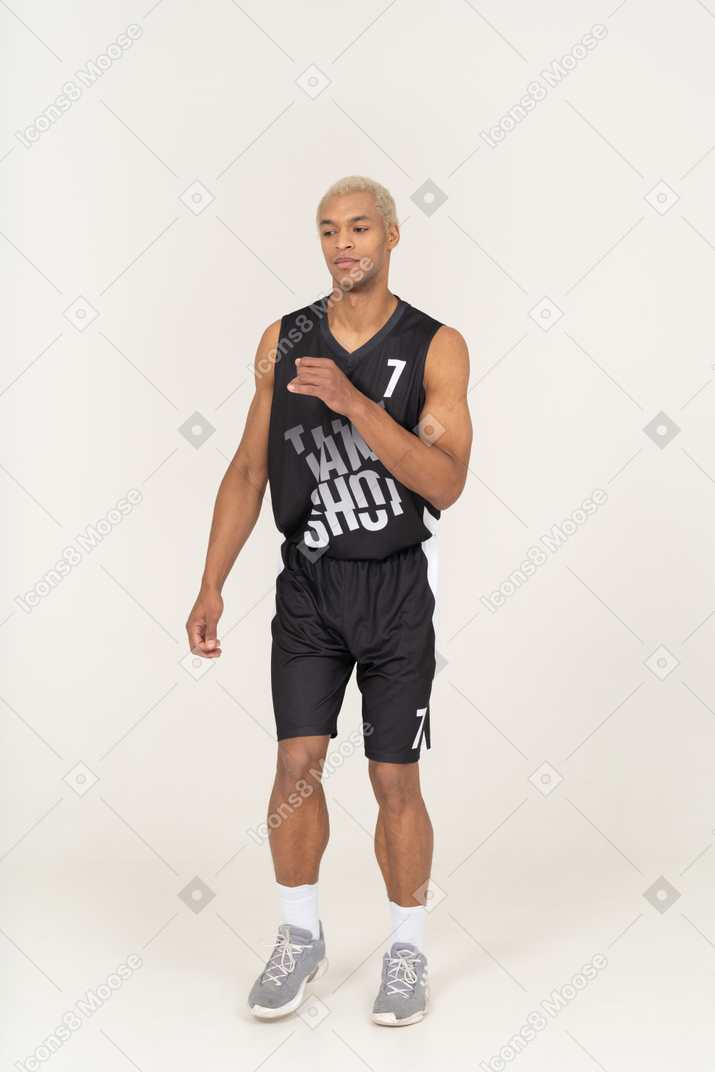 Front view of a walking young male basketball player raising hand
