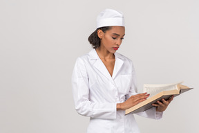 Atraente médico feminino procurando algo em um livro