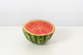 A half of a sweet ripe watermelon, lying isolated against a white background, looking nice and yummy