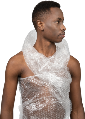 A portrait of a naked african young man wrapped in plastic