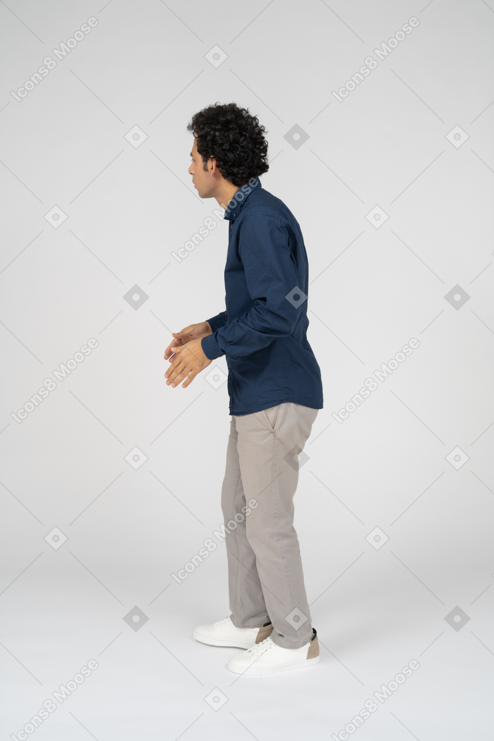Uomo in abiti casual in piedi di profilo e fissando qualcosa
