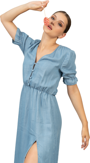 Vista di tre quarti di una giovane donna in abito blu che tiene un lecca-lecca