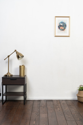 A nice and simple room with white walls, wooden floor and a brass lamp on the nightstand