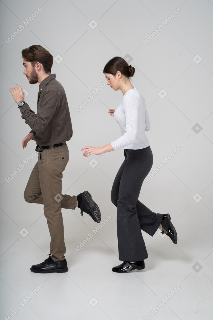 Vista lateral de um jovem casal com roupa de escritório levantando a perna