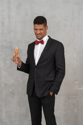 Repulsed young man standing with a glass of champagne