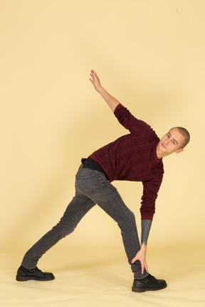 Full-length of a young man in a red pullover stretching his back