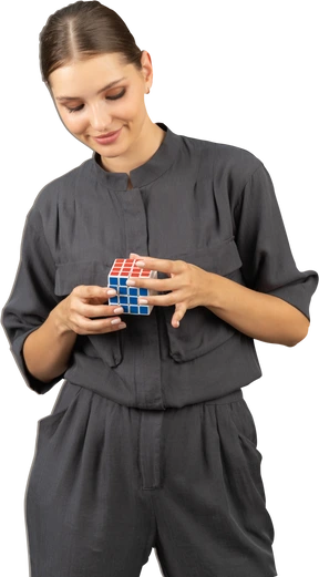 Front view of a smiling young woman in a jumpsuit holding the rubik's cube
