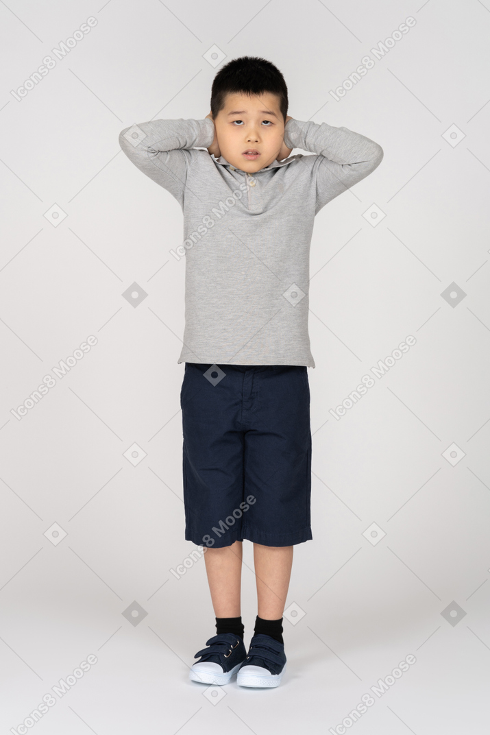 Boy covering ears while looking at camera