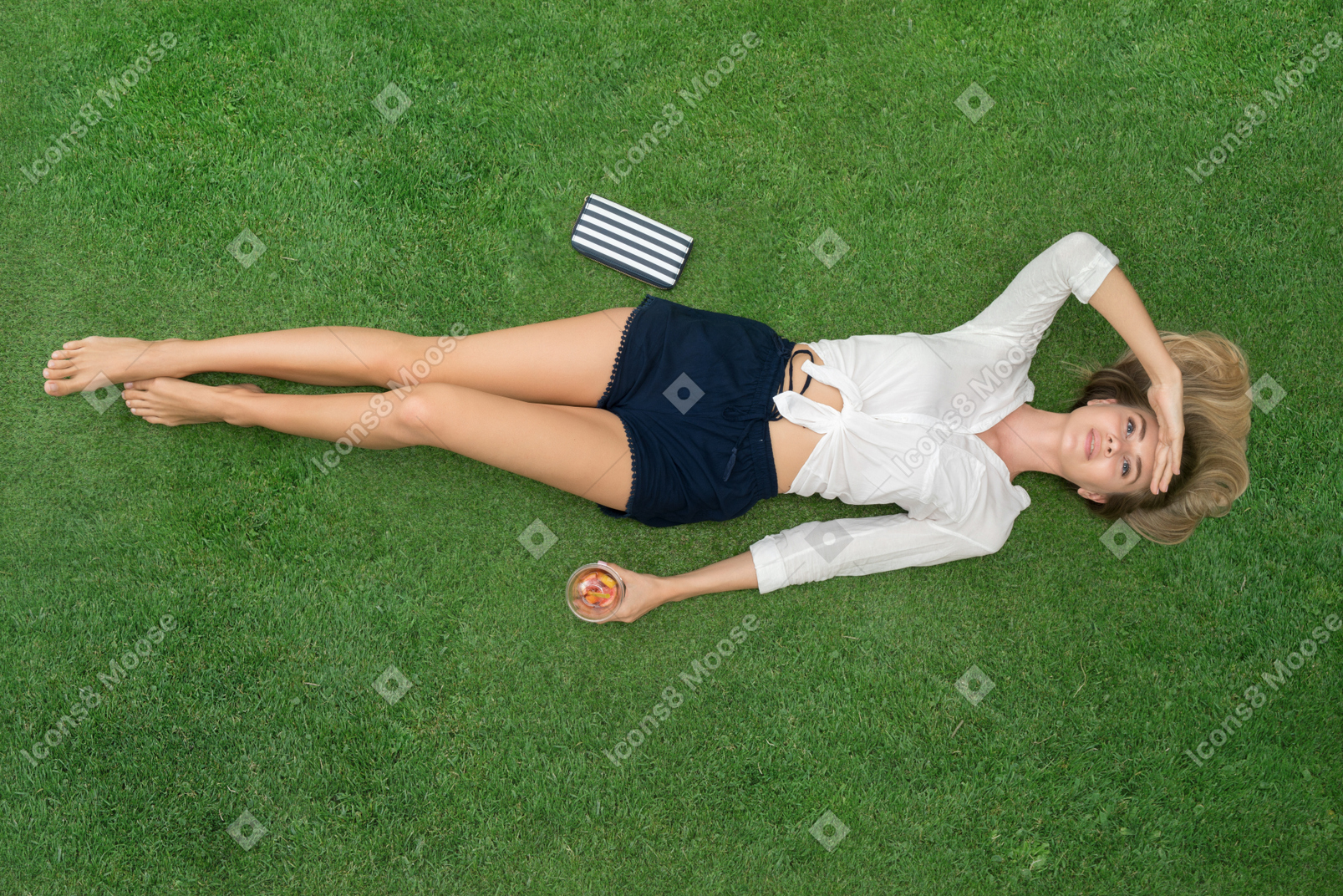 Привлекательная молодая женщина лежит на спине на траве