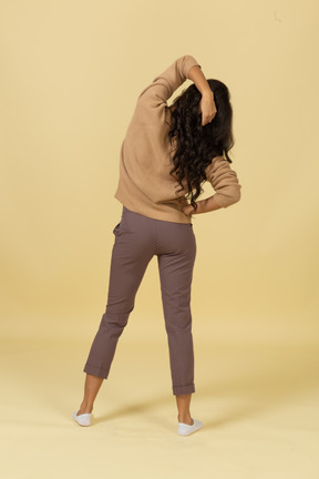 Back view of a dark-skinned young female touching hair
