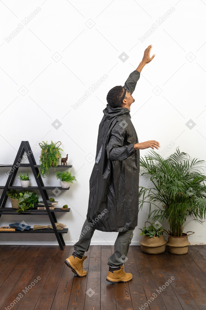 Vista traseira de um homem de capa de chuva com os braços levantados