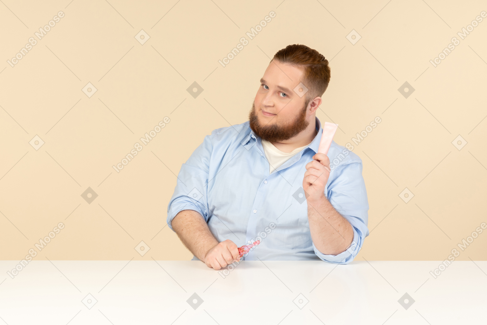 Big man sitting at the table and holding toothpaste and toothbrush