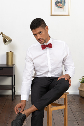 A man in a white shirt and red bow tie sitting on a chair