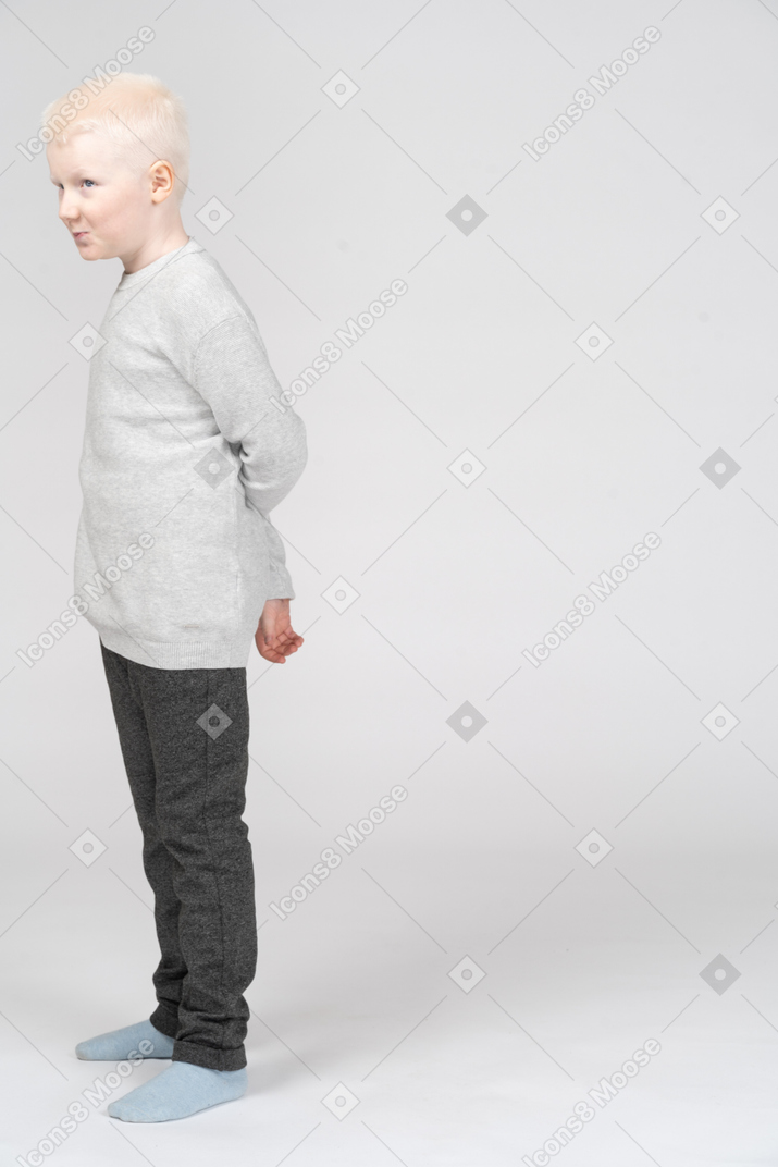 Little boy looking away with his hands behind back