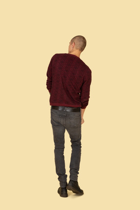 Back view of a walking young man in red pullover