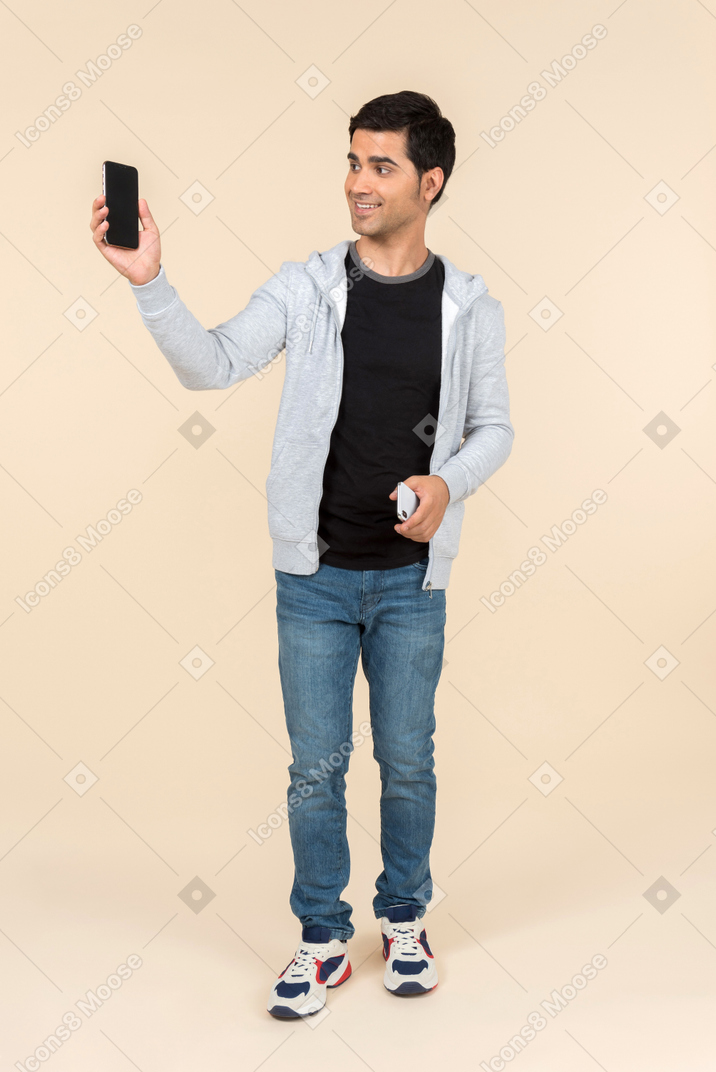Junger kaukasischer mann, der zwei smartphones hält