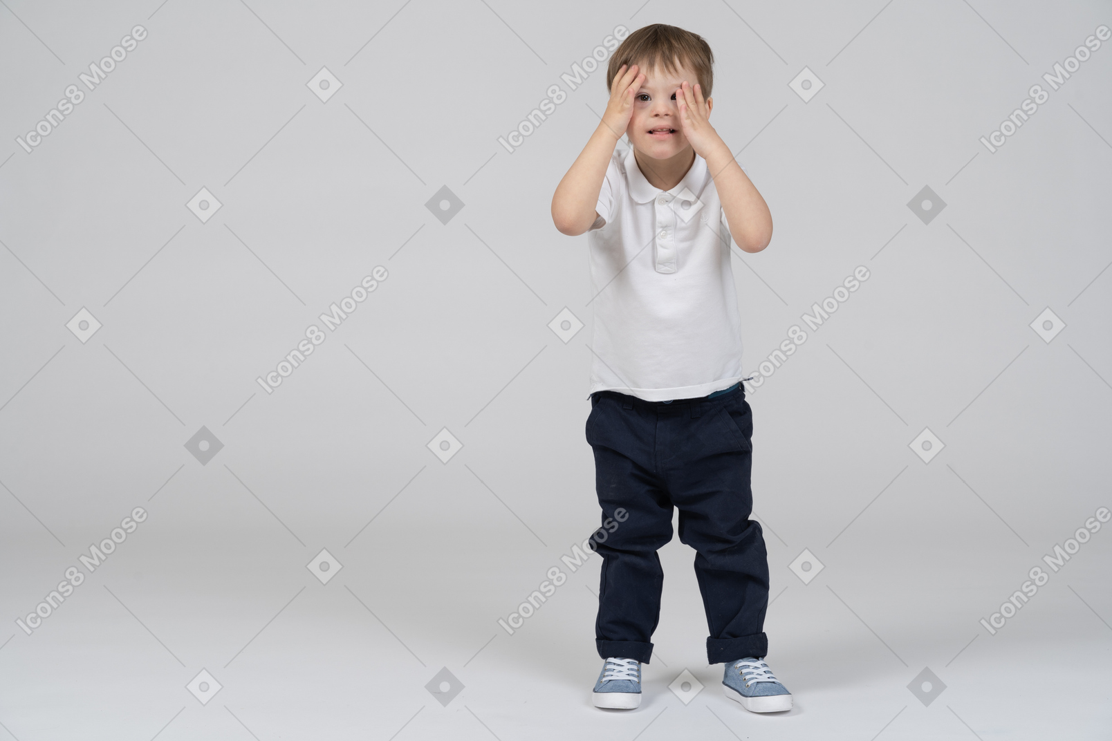 Маленький мальчик стоит с руками на лице